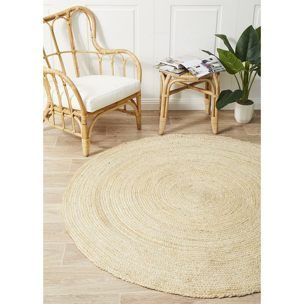 Round hand-woven natural jute rug in bleached beige with subtle texture on light wood floor.