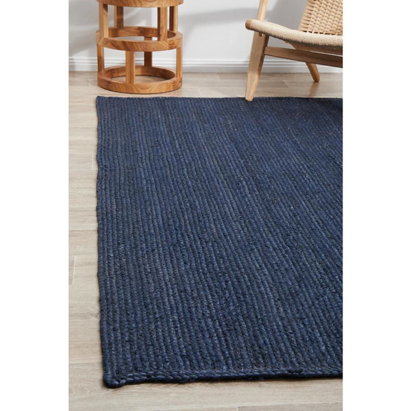 Navy blue hand-braided jute rug with textured pile on light wood floor.