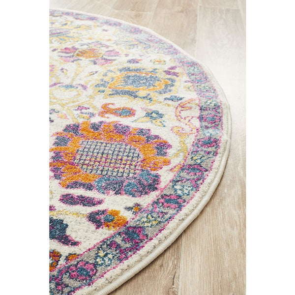 Round bohemian rug with pink, purple, orange, and blue floral patterns on a cream background.