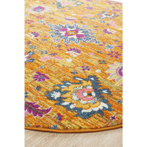 Rust pink round bohemian rug with multicolored floral and geometric patterns on a textured background.