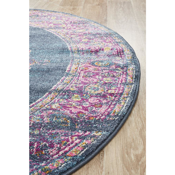 Round navy blue rug with vibrant multicolor bohemian pattern on wood floor.