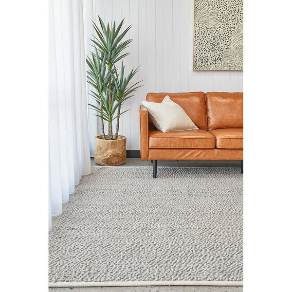 Light grey boucle wool blend rug with textured pile in a modern living room setting.