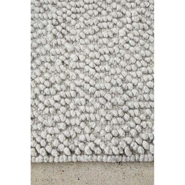 Grey wool blend rug with boucle texture and hand-woven pattern.