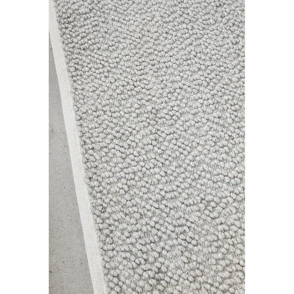 Grey boucle wool blend rug with textured hand-woven pile and natural soft loops.