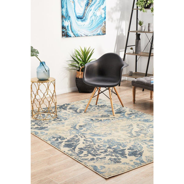 Blue and beige floral patterned modern rug in living room setting with plant and black chair.