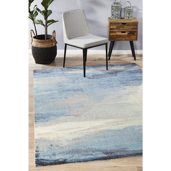 Abstract watercolor rug in blue, beige, and grey tones with a soft, blended pattern.