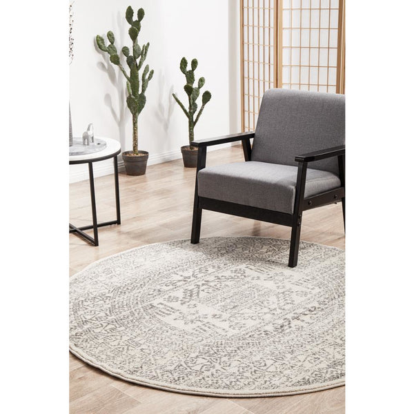 Round silver grey rug with intricate modern tribal pattern in living room setting.