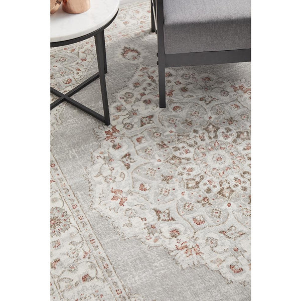 Rectangular rose beige and grey rug with intricate transitional floral and medallion pattern under side table and chair.