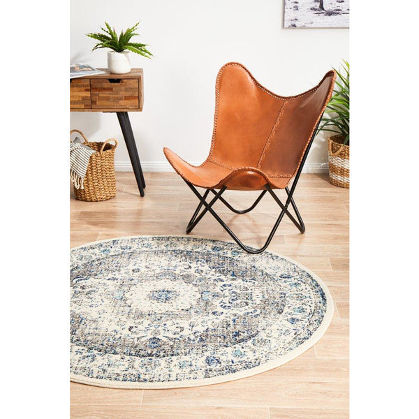 Round transitional rug with beige, blue, and grey intricate pattern on light wooden floor.