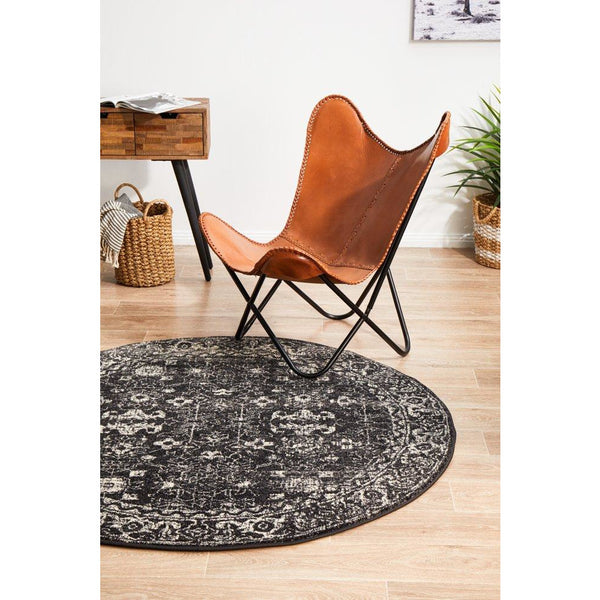 Round charcoal transitional rug with intricate patterned design on light wood floor.