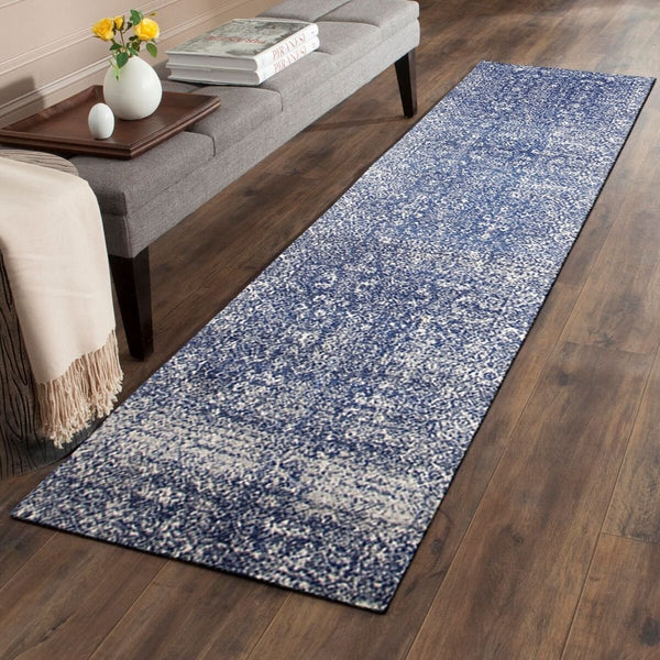 Navy blue patterned transitional runner rug on hardwood floor beside gray sofa and wooden bench.