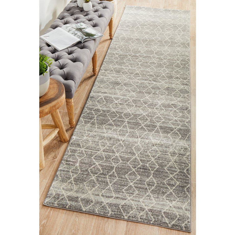 Grey patterned transitional runner rug with geometric design on wooden floor near tufted bench.