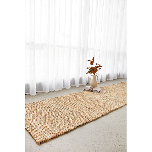 Natural woven jute runner rug with a chunky braided texture on a light floor.