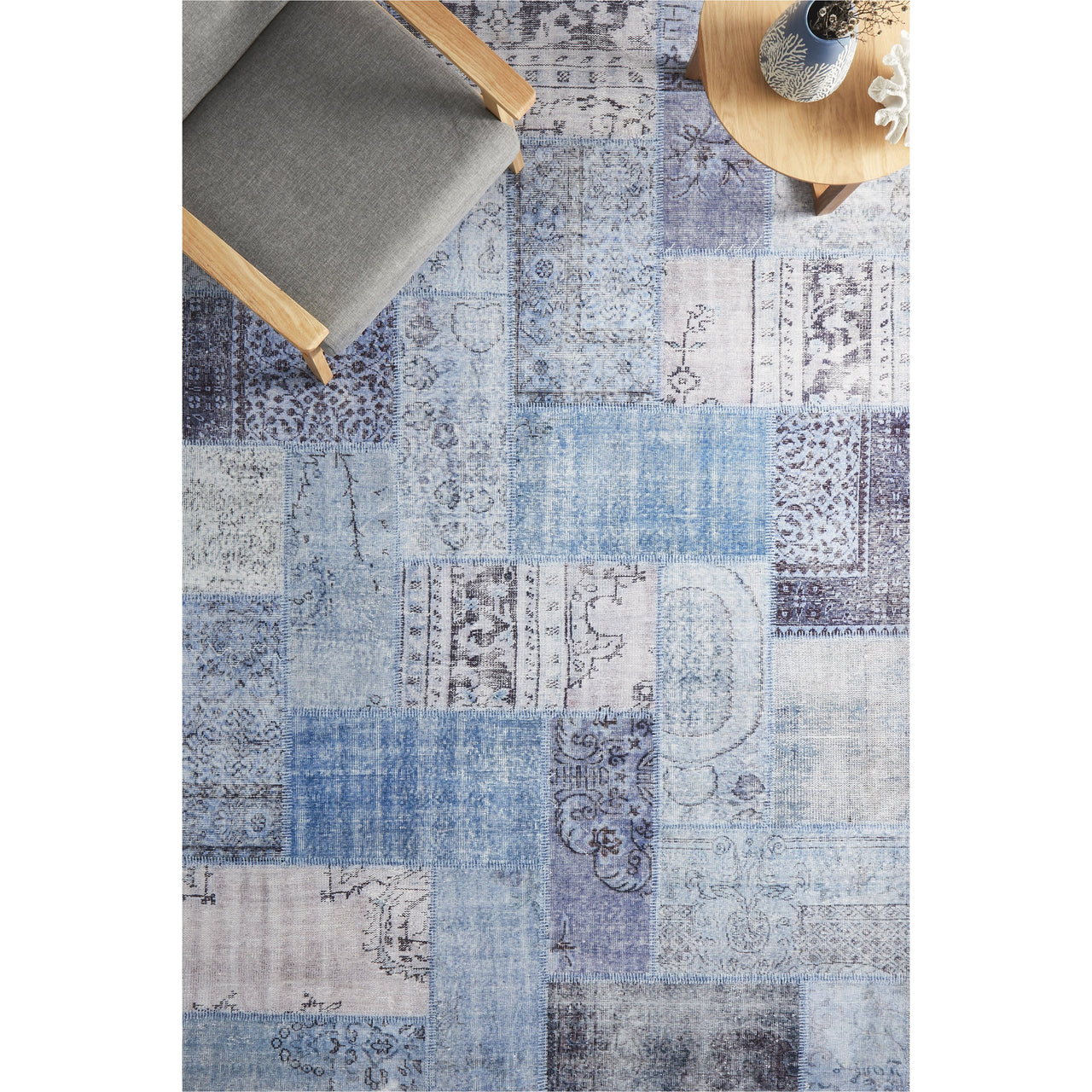 Rectangular denim blue patchwork rug with varied geometric and floral patterns in soft muted tones.