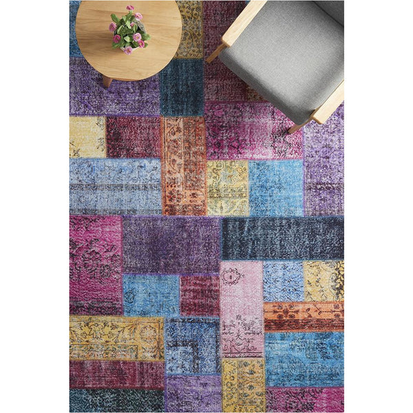 Colorful patchwork rug with geometric tribal patterns in blue, purple, pink, yellow, and orange tones.