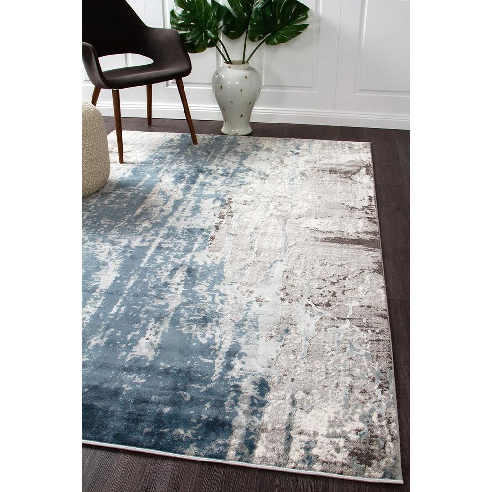 Blue, beige, and grey abstract patterned modern rug with a distressed textured look on dark hardwood floor.