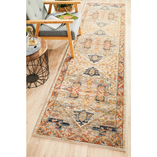 Rust and multi-color tribal patterned transitional runner rug on light wood floor by mid-century modern chair and side table.