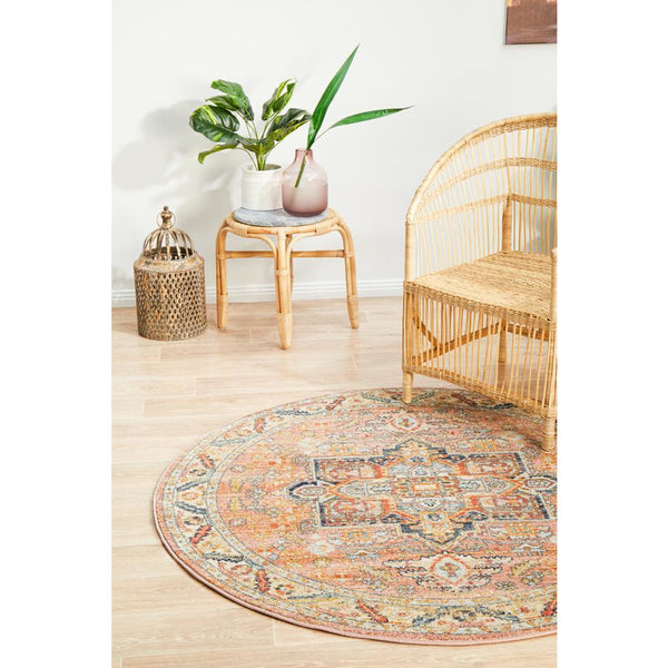 Round transitional rug with multicolored tribal patterns in earth tones on light wood floor.