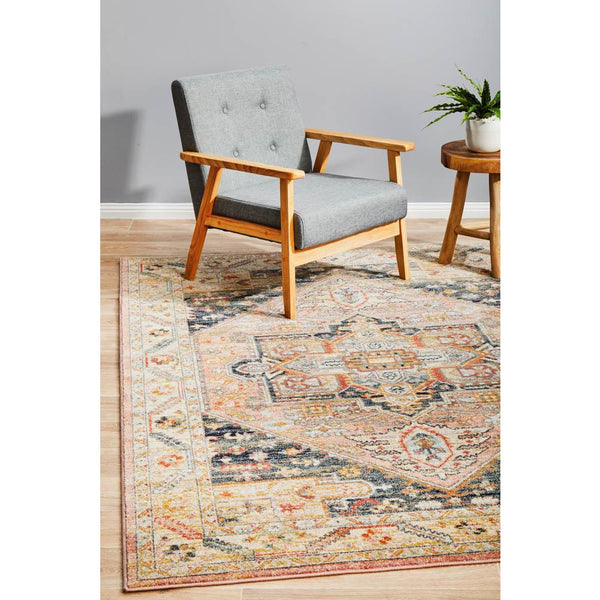Transitional multi-colour rug with aztec-inspired tribal patterns in earth tones under a wooden-framed grey upholstered.