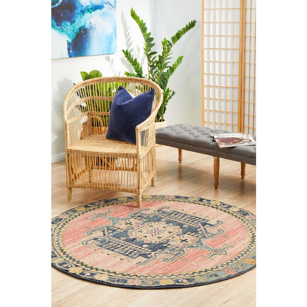 Round transitional rug with blue, rose, and beige tribal patterns on a wood floor.