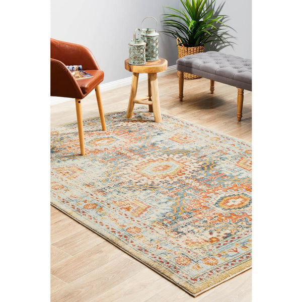Rectangular blue and terracotta multi-color transitional rug with tribal-inspired pattern on light wood floor.