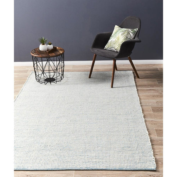 Turquoise blue flatwoven wool rug with subtle textured weave on wooden floor.