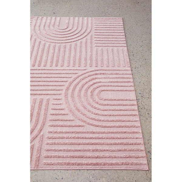 Rectangular blush pink rug with modern geometric curved and linear patterns in textured polypropylene pile.