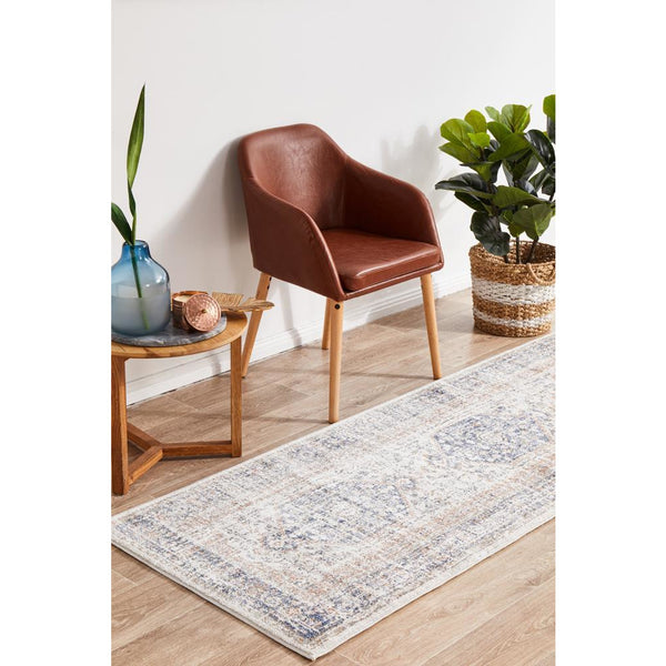 Transitional runner rug with blue and peach medallion pattern on light background, set on wooden floor.