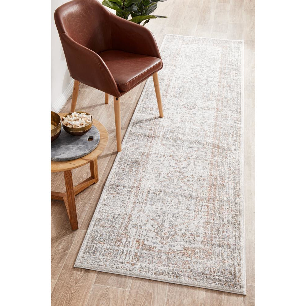 Transitional runner rug with silver grey, soft blue, and warm peach medallion pattern on light background.