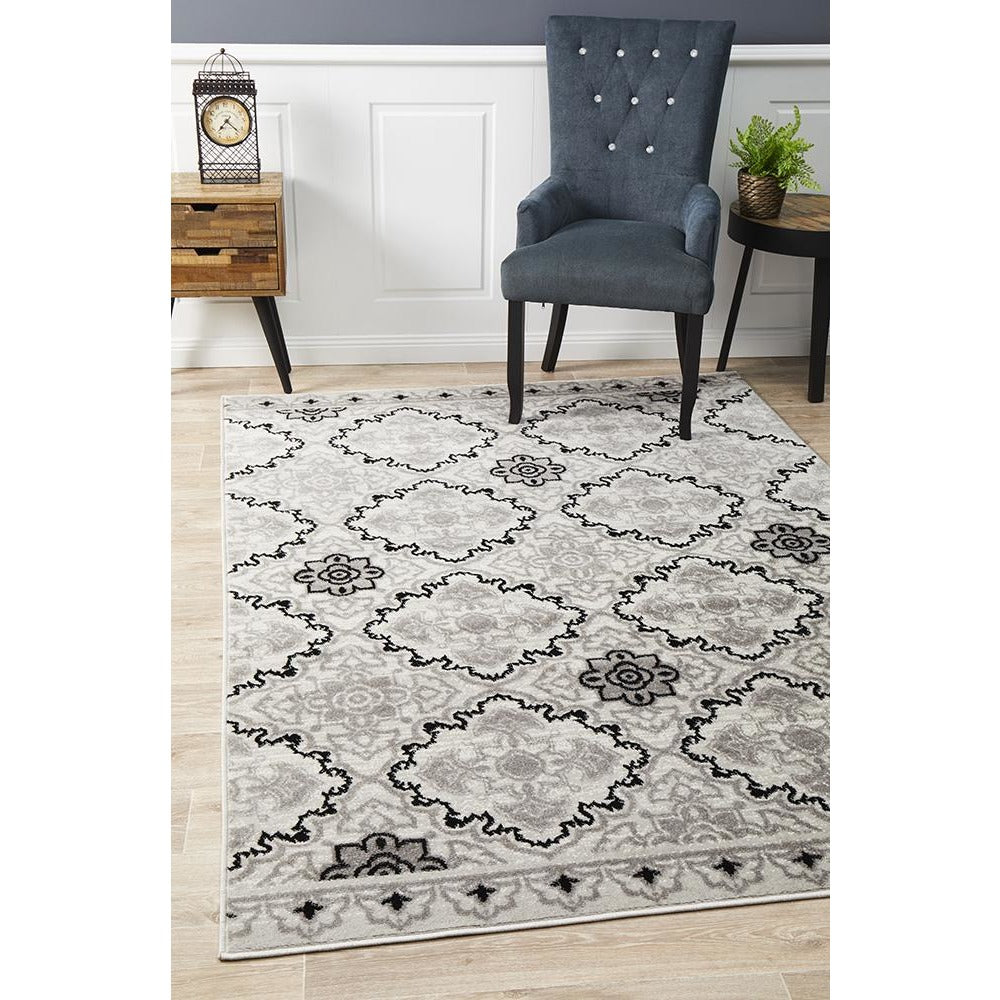 Black, beige, and grey abstract floral pattern on a modern rectangular rug in a living room setting.