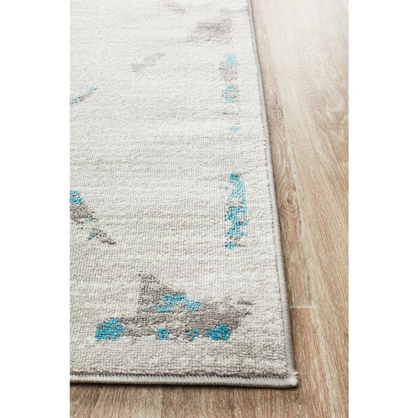 Beige and blue abstract diamond patterned rug with modern geometric shapes on light background.