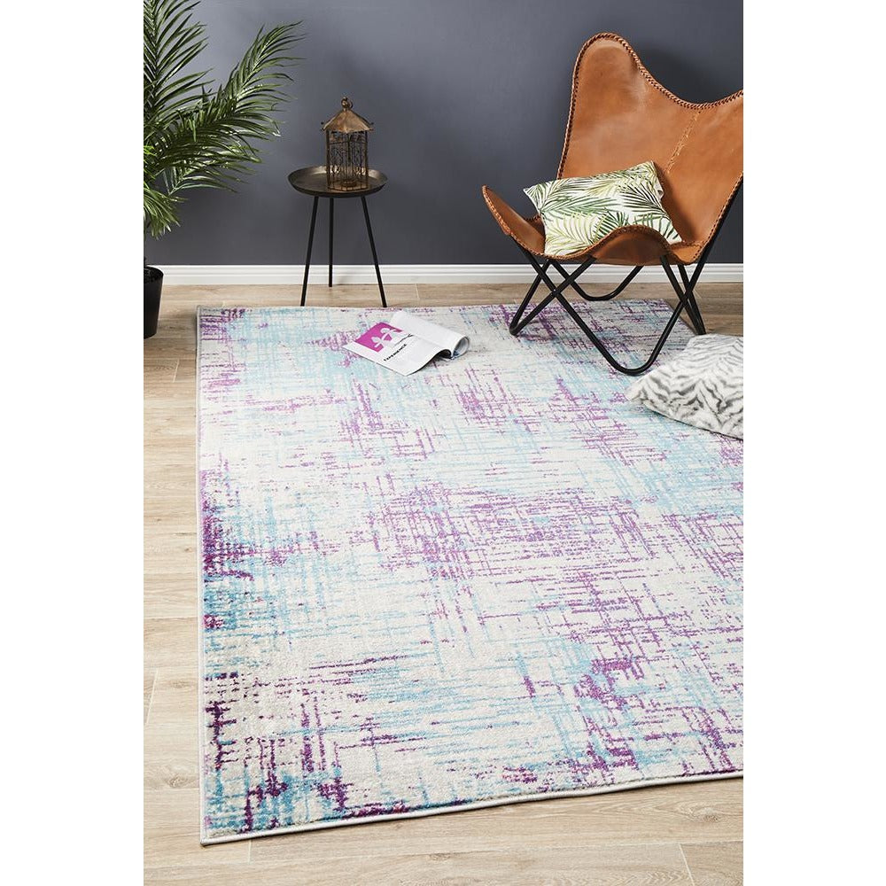 Purple, blue, and beige abstract patterned rug with a textured, modern design on light hardwood floor.