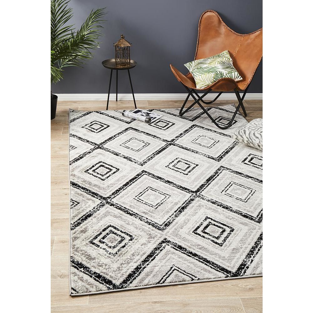 Black, beige, and grey diamond patterned modern abstract rug on light wood floor.
