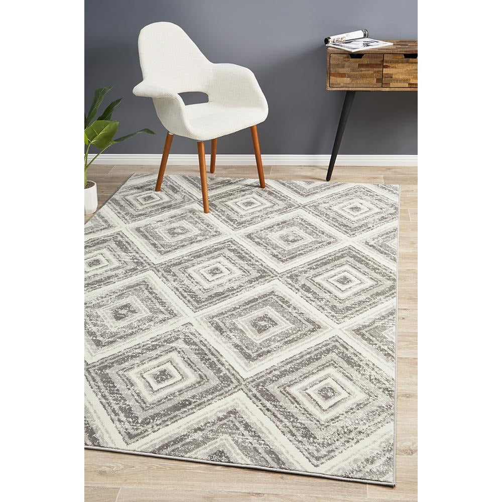 Grey and beige diamond patterned modern abstract rug on light wood floor.