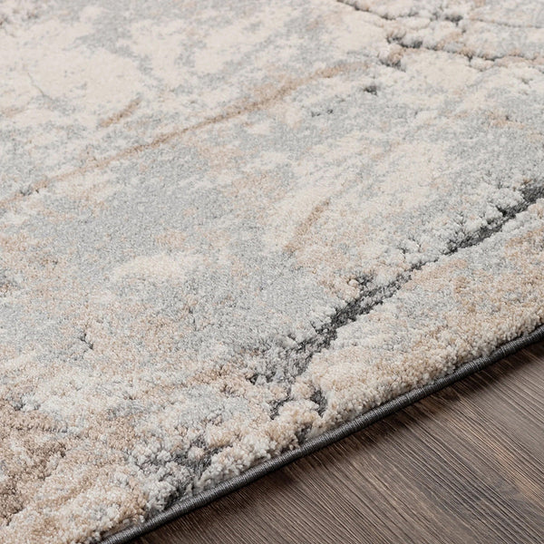Close-up of textured modern rug with abstract pattern in soft beige, grey, and cream tones on wooden floor.