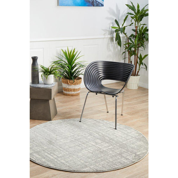 Round silver grey rug with subtle abstract patterns on light wood floor.