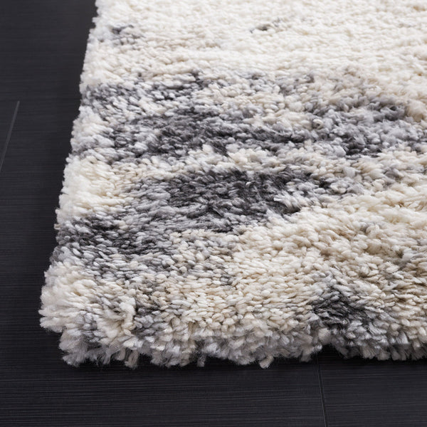 Close-up of a white and gray modern abstract patterned shaggy rug with a thick polypropylene pile on a dark floor.