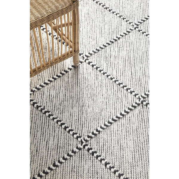 Ivory wool blend rug with black trellis pattern and textured flatwoven design.