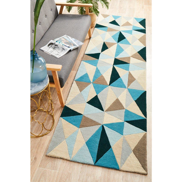 Blue multi-color geometric pattern wool runner rug on light wood floor next to gray sofa and gold side table.