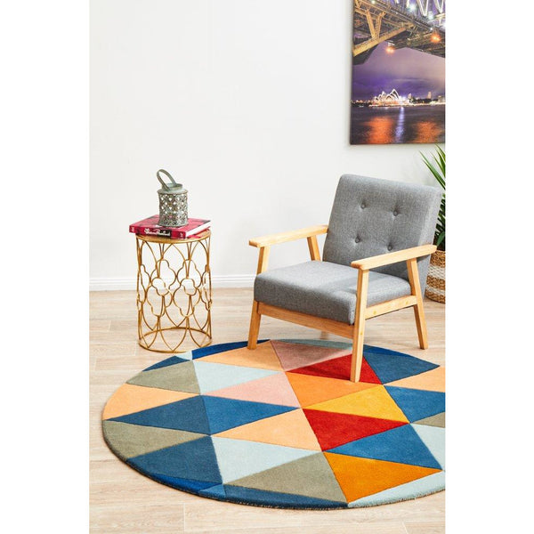 Round wool rug featuring a rust, blue, navy, and beige geometric pattern on hardwood floor.
