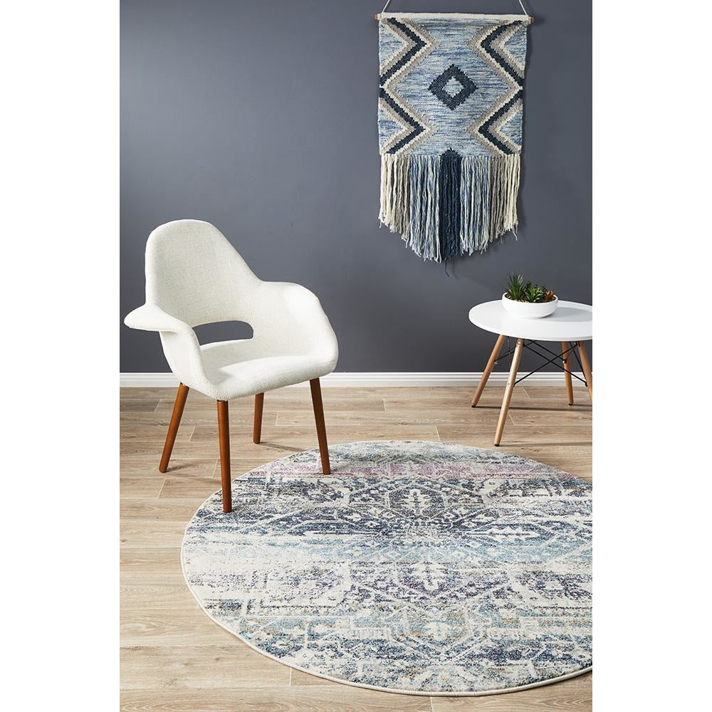 Round bohemian blue rug with navy and cream geometric patterns and fringed edges.