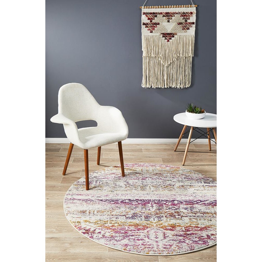 Round bohemian rug with fuchsia, cream, and purple patterns on wood floor.