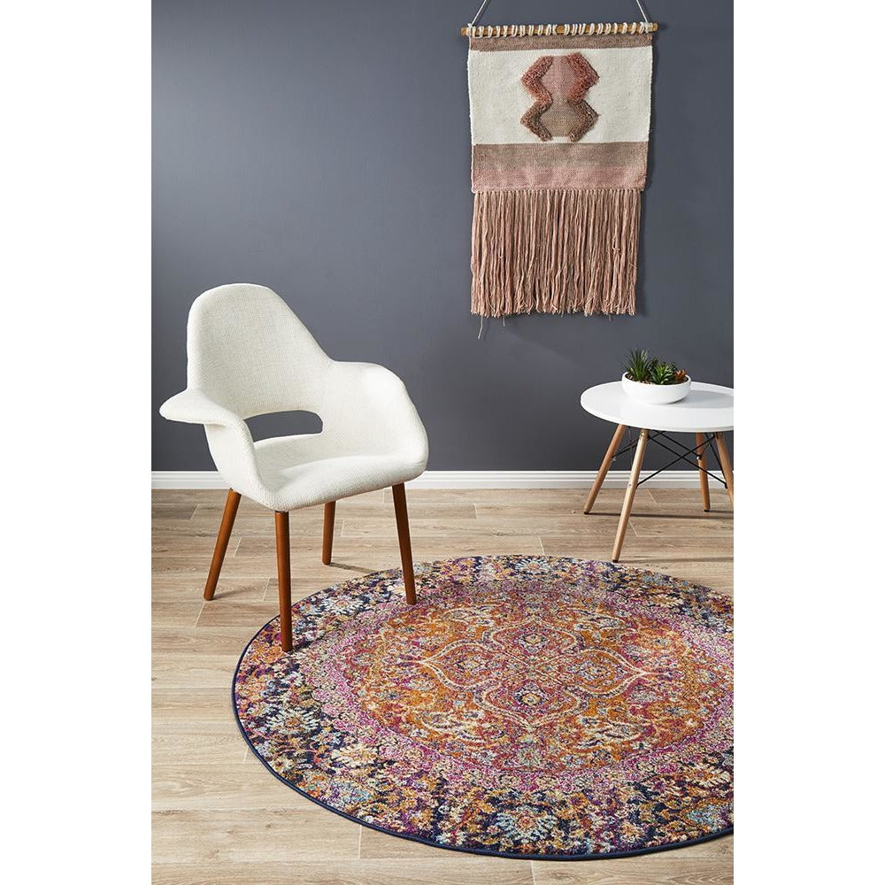 Round transitional bohemian rug in pink and rust with intricate multicolored patterns and a black border.