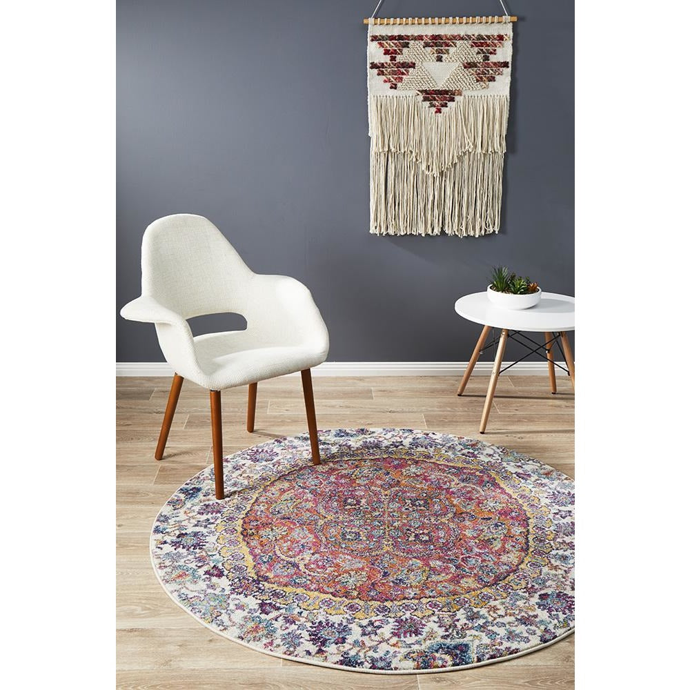 Round bohemian rug with rust, beige, and multicolored intricate patterns on light wood floor.
