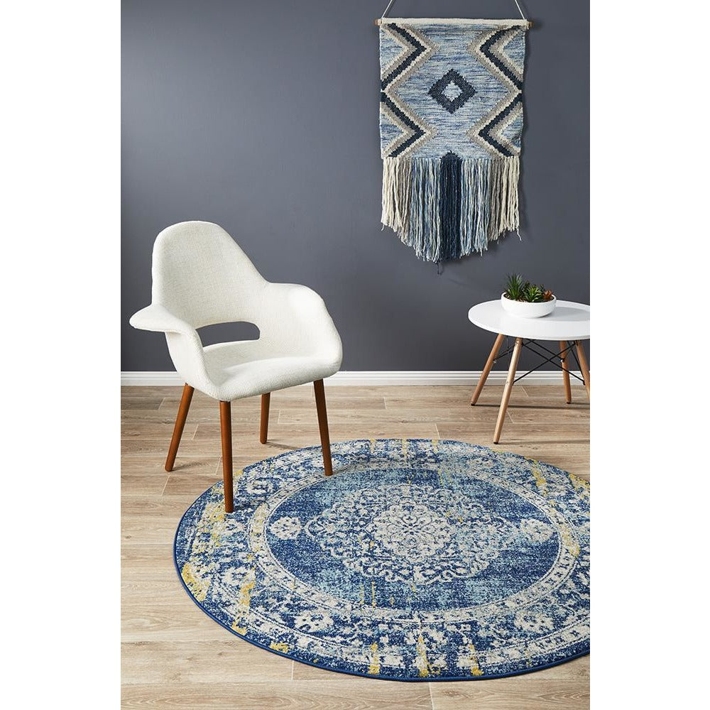 Round navy blue rug with intricate bohemian patterns in cream and beige tones on wooden floor.
