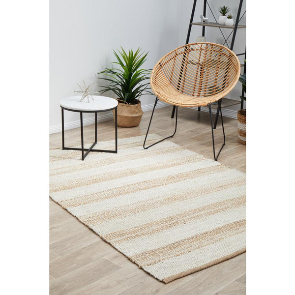 Rectangular hand-braided jute rug with natural and white striped pattern on wooden floor.