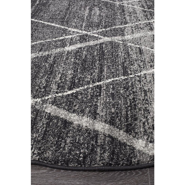Round charcoal grey rug with abstract white lattice tribal pattern, textured polypropylene surface.