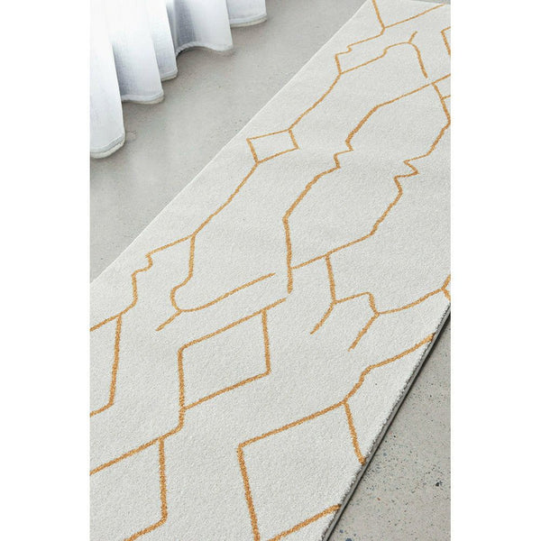 White and gold modern runner rug with geometric line pattern on concrete floor.