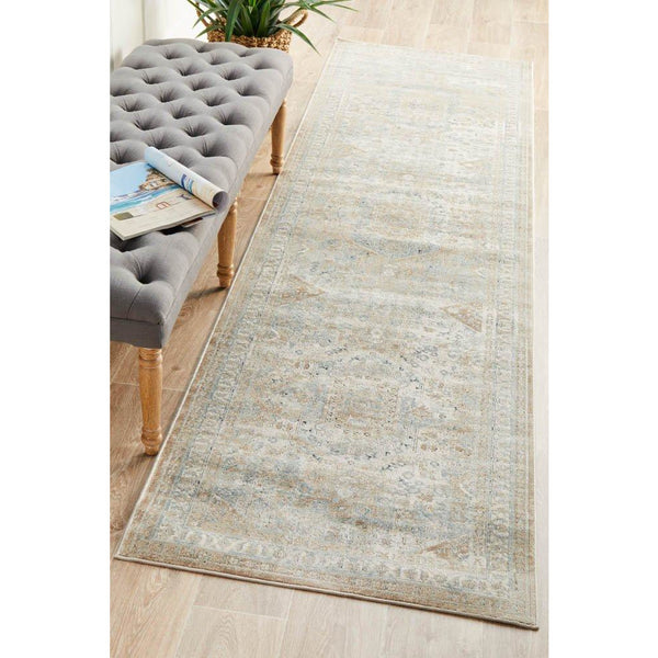 Beige and green faded traditional patterned runner rug with decorative border on light wood floor.