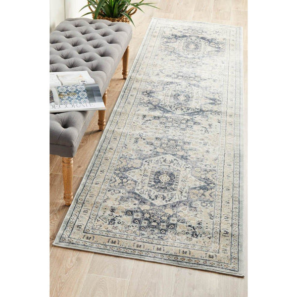 Blue and beige traditional patterned rug with faded wash and detailed border on light wood floor.